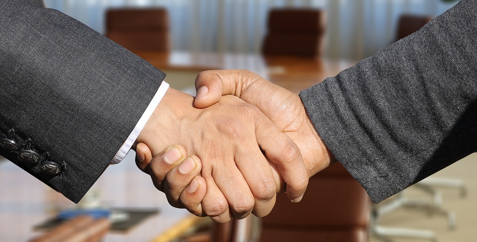 Image contains two arms shaking hands